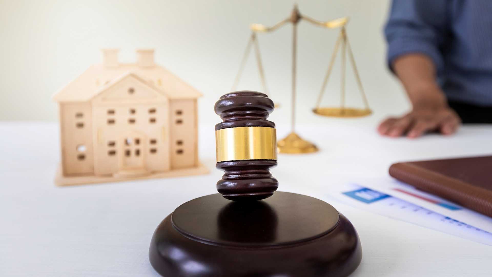 a%20gavel%20legal%20balance%20and%20wooden%20home%20figurine%20on%20a%20desk